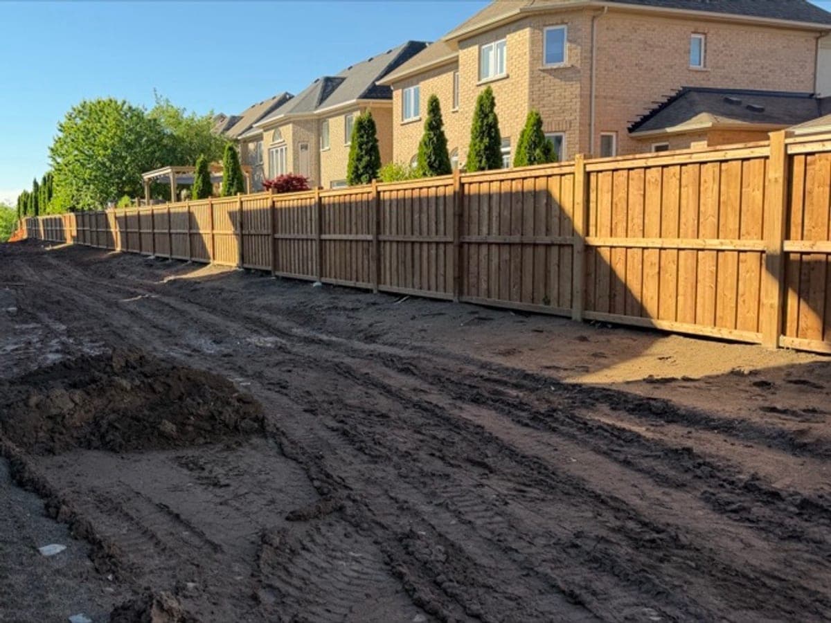 Brown pressure-treated privacy fence installed along new-build homes