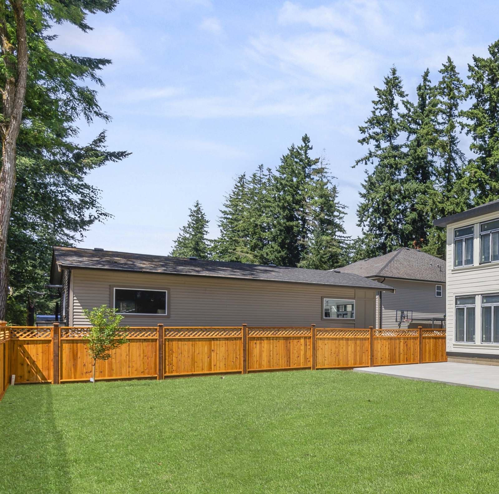 Diagonal lattice-top cedar fence running the length of a landscaped backyard