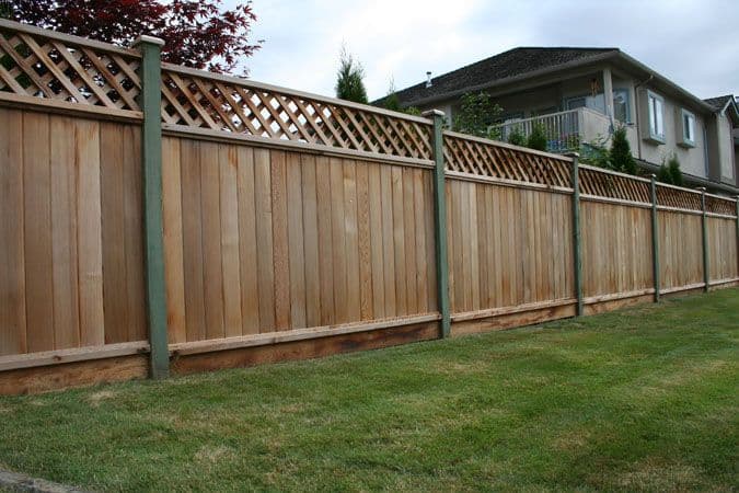 Long diagonal lattice-top cedar fence run on a sloped yard