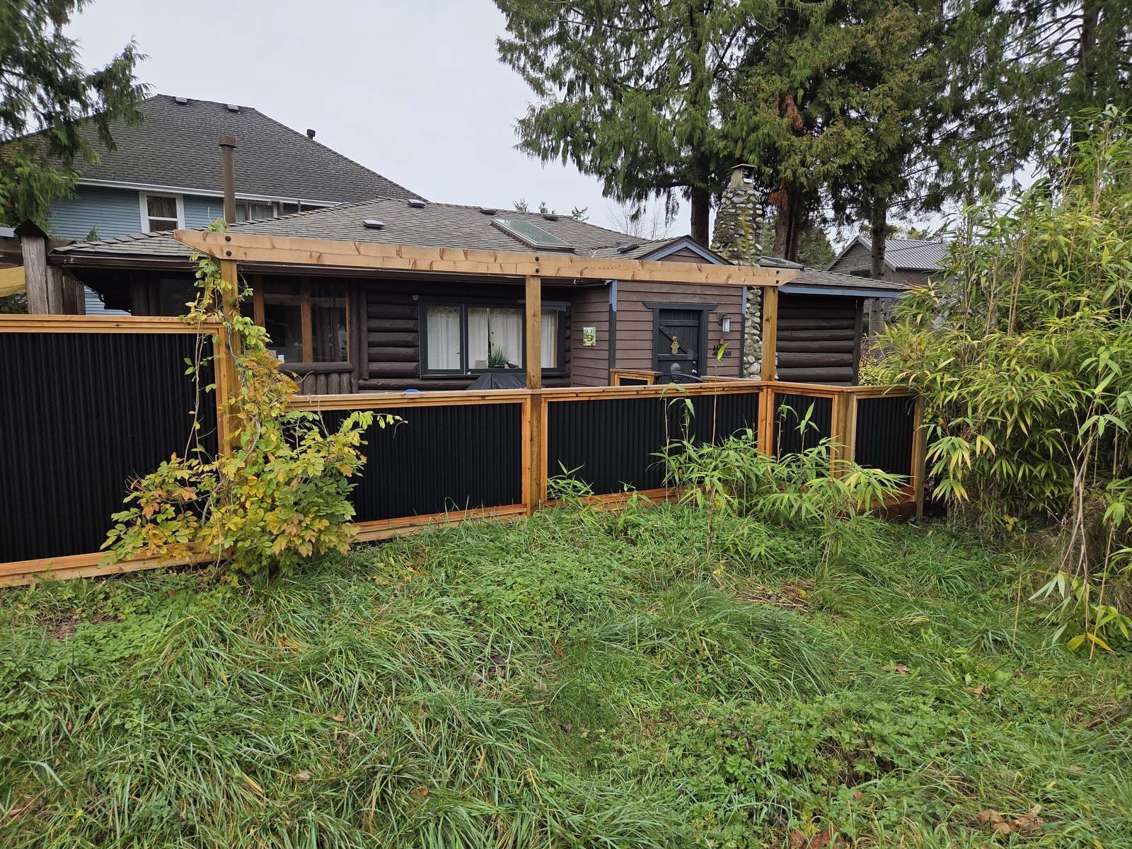 Wood and steel fence panels enclosing a wooded cabin property