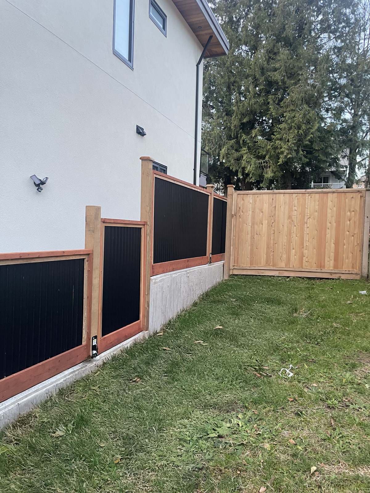 Wood and steel fence panels with a solid cedar gate along a side yard