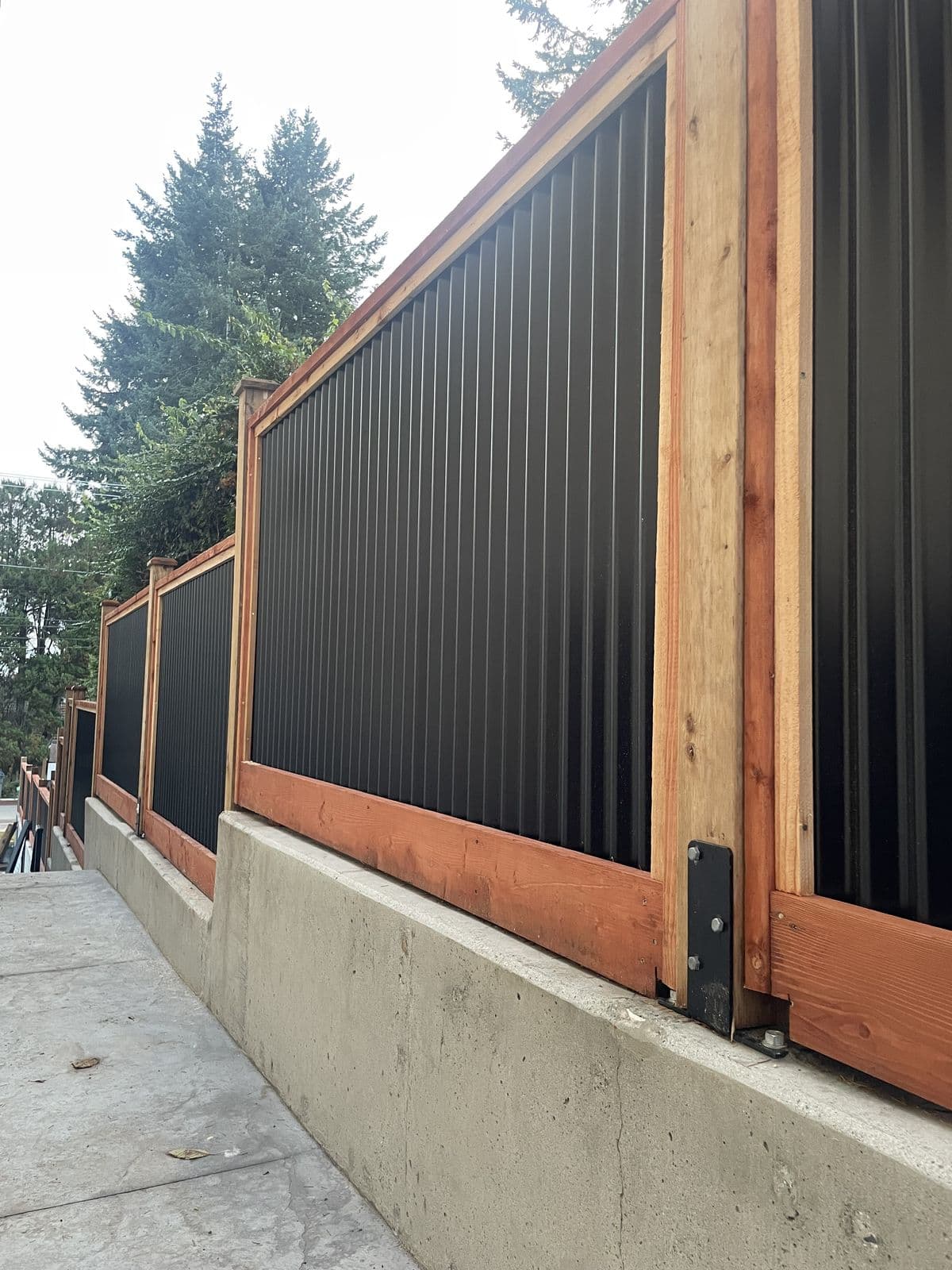 Close view of black corrugated steel fence panels in a cedar frame