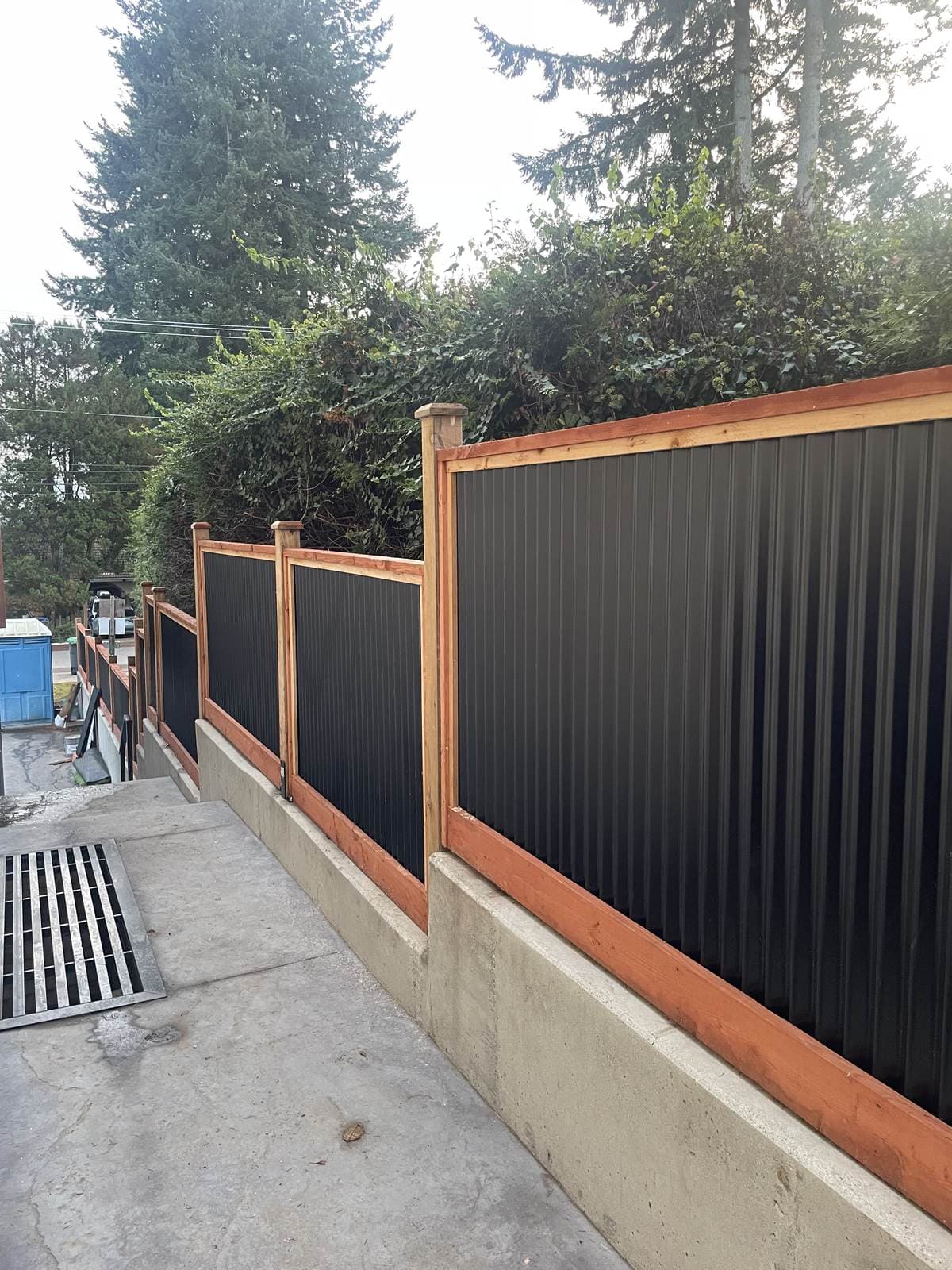 Wood and steel fence line running along a driveway